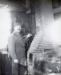 John Perry inside Asa Sheldon's Blacksmith shop in fron of a chimney